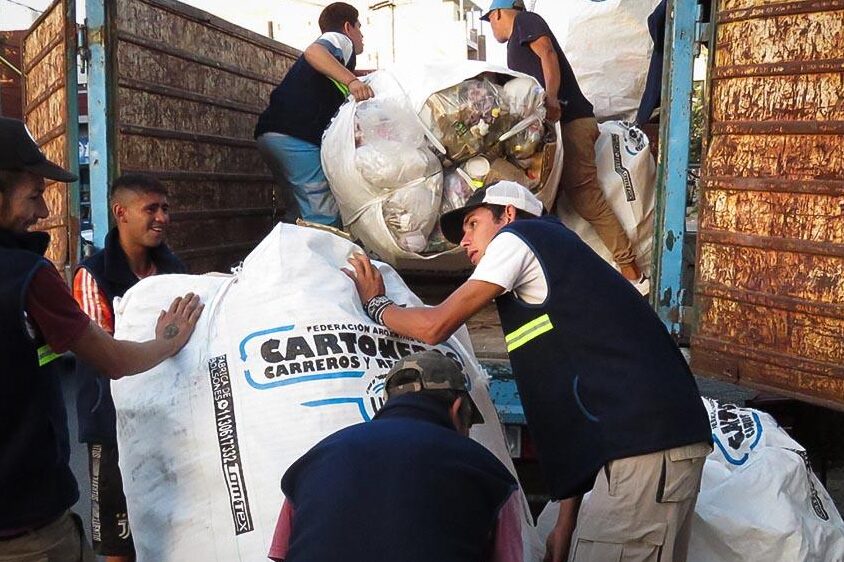 Varios cartoneros suben bolsones con materiales reciclables a un camión