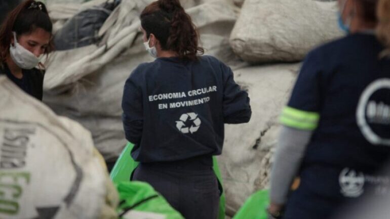 tres recuperadoras urbanas en sus uniformes separan residuos al frente de bolsones de materiales